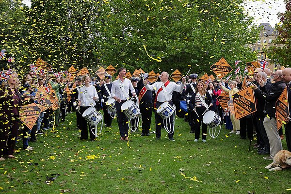 Ed Davey leads a marching band surrounded by Lib Dem activists and confetti