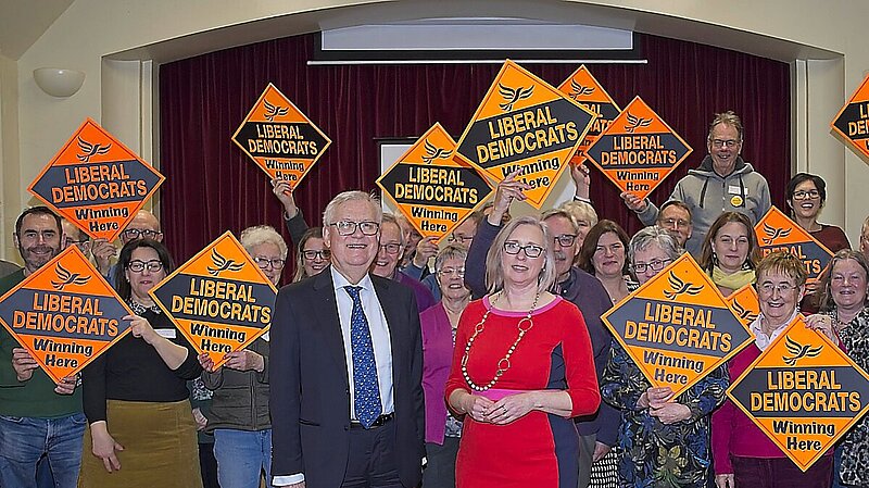 Lord Dick Newby with Jenny Wilkinson in front of enthusiastic Lib Dems waving Lib Dem diamonds