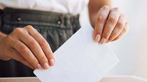A person putting a ballot paper into a ballot box